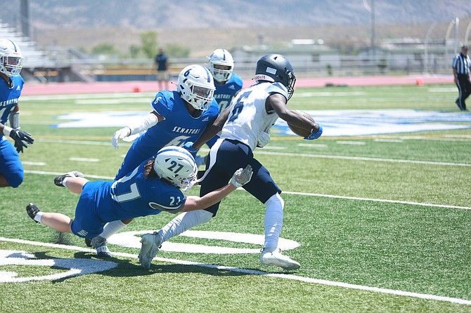 Ean Thomas (27) and Kekoa Mitchell (6) combine for a tackle against Canyon Springs on Saturday in Carson High football’s season opener. The Senators did not allow a point in a 27-0 win over the Pioneers.