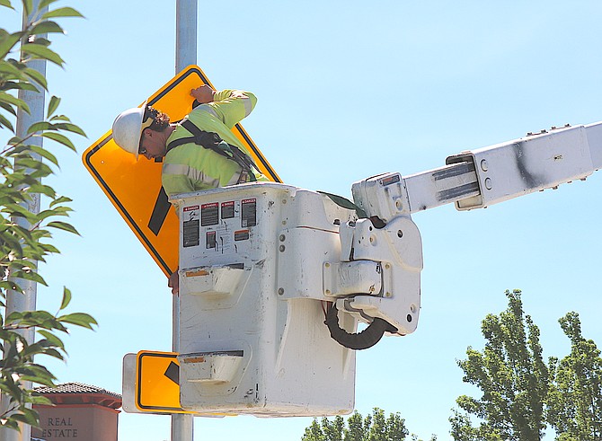 A worker installs a crosswalk sign on Highway 395 at Kings Lane in Gardnerville on Thursday.