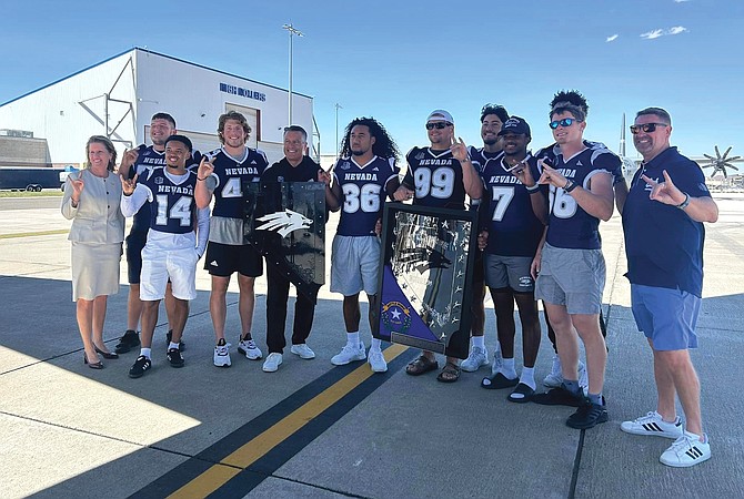 Athletic Director Stephanie Rempe, University of Nevada President Brian Sandoval, fourth from right, and Wolf Pack football coach Jeff Choate pose with nine players in a special dedication of the Battle Born Shield at the Nevada Air National Guard base on Aug. 23.