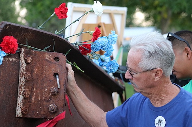 A man touches a piece of beam from the World Trade Center at the 9/11 Remembrance Ceremony at Mills Park in 2023.