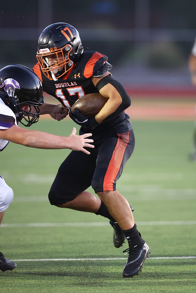 Evan Youmans stiff arms a Spring Creek defender last week. Youmans and the Tigers defeated North Valleys Friday night, 56-32.