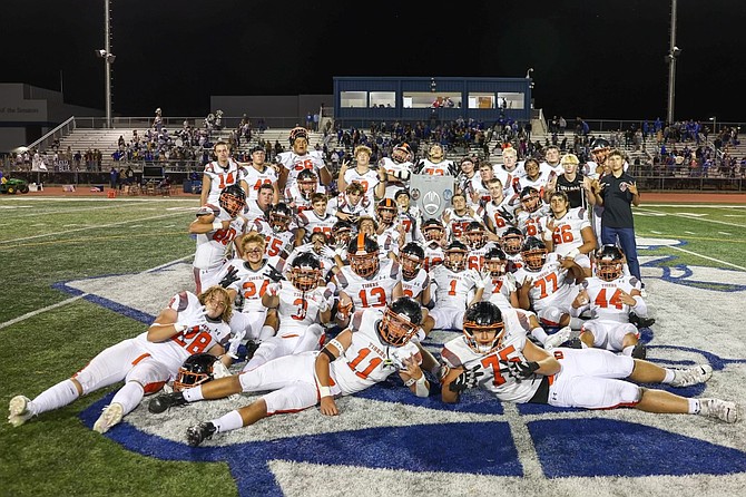 The Douglas High School football team poses in front of The Rivalry Trophy after beating Carson, 47-13, in Carson Friday night.