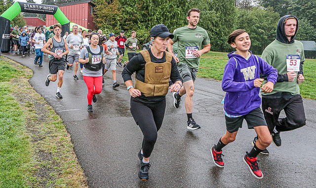 Braedan Gardner, 20, of Everett (at right in green hoodie) and Zachary Verge, 27, of Everett (in green T-shirt), as well as a happy UW fan run in the first part of the start of the 
9/11 Heroes 5K Run held Sept. 14 at Willis Tucker Park in Snohomish. The Travis Manion Foundation veteran service organization organizes the run to honor the lives lost on Sept. 11, 2001 and in the wars since.
The 5K‘s overall winner was Jason Labusky with a time of 20 minutes 42 seconds.
Joan Lindell Olsen, 56 of Kirkland, was the overall female winner with a time of 20 minutes and 50 seconds. Justice Perkins, 26 of Issaquah, finished second overall in the male division with a time of 21 minutes and 23 seconds.