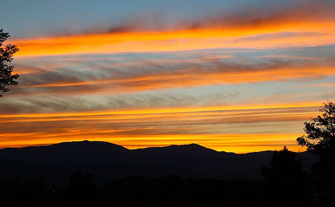 Clouds paint pink and orange strokes across Monday morning's sunrise over the Pine Nut Mountains.