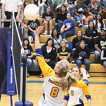 Lowry’s Kyra Schiermeister tips the ball over the net during Friday’s match with Spring Creek