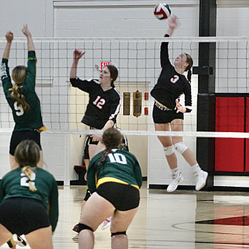 Raegan Burrows (3) leaps to the net backed by Aaliyah Allen (14) and Kyra Cerini (12).