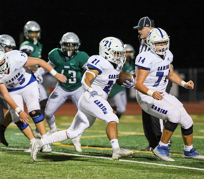 Carson High’s Christian Rey (21) carries the ball against Hug earlier this season while lineman Aaron Linehan (74) looks for a block. Rey has 340 yards and eight touchdowns on the ground for the Senators.