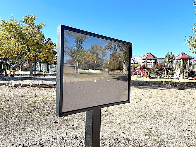 One of the story signs at the Lampe Park playground reflects the park.