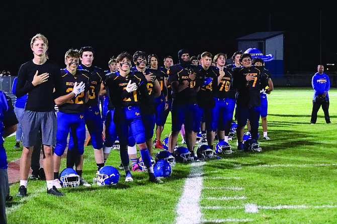 The Lowry High School football team stands together for the National Anthem prior to the start of Friday's home game against Fernley.