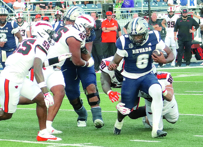 Nevada running back Savion Red looks for room against Oregon State linebackers Semisi Saluni (45) and Dexter Foster (55) in Saturday’s game against the Beavers. Red finished the game with four touchdowns.