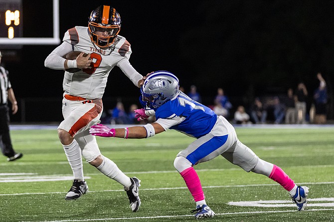 Douglas High School quarterback Jackson Ovard stiff arms a McQueen defender, during the Tigers’ 49-21 win over the Lancers. Ovard and company face a big test at home this week against Reed.