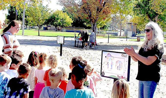 Former Douglas County Library trustee and member of the Library Gala Committee Starla Doughty, leads the children from the Douglas County Community Center’s Sagebrush Sprouts Preschool during the Douglas County Library’s first Story Walk at Lampe Park on Tuesday.