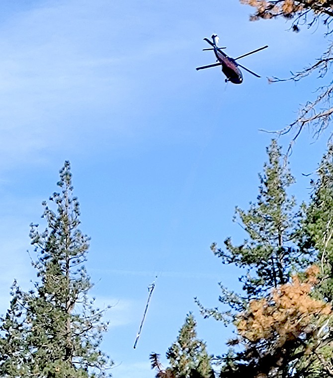 A helicopter flies a power pole into a job site in this photo taken by Ellie Waller.