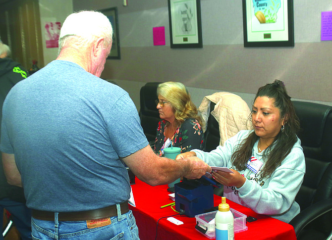 An election worker verifies a voter’s signature during last week’s early voting at the Churchill County commission chambers.