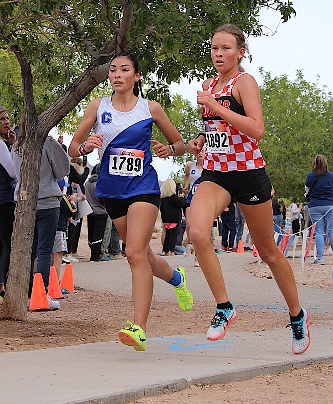 Douglas High’s Lucy Nord runs next to Carson’s Brianna Rodriguez-Nunez at the Class 5A state cross country meet Saturday in Boulder City. Nord finished ninth overall as the Douglas girls team was fifth as a unit.