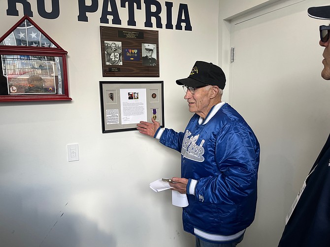 Charles Burr, a classmate of Frederick Williams at the University of Nevada in the 1960s, ponits to a bottom photo of Marine Lance Cpl. Kielin Dunn’s Purple Heart and a letter written to Nevada football coach Jeff Choate by his mother. The top photo is a tribute to Williams and his playing career as a Wolf Pack halfback.