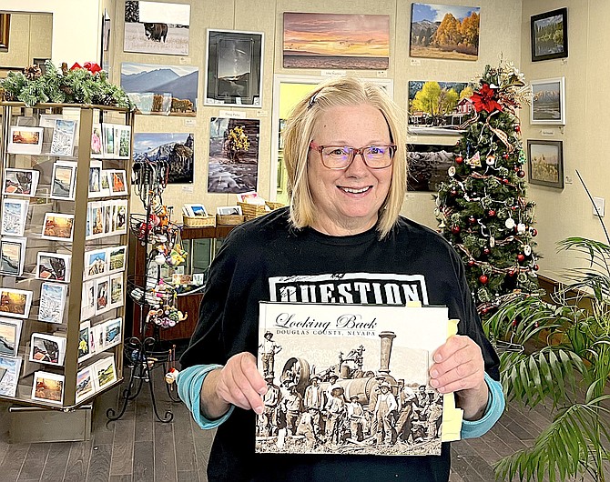 East Fork Gallery artist Helen Yoder holds a copy of The Record-Courier’s ‘Looking Back’ history book from 2007.