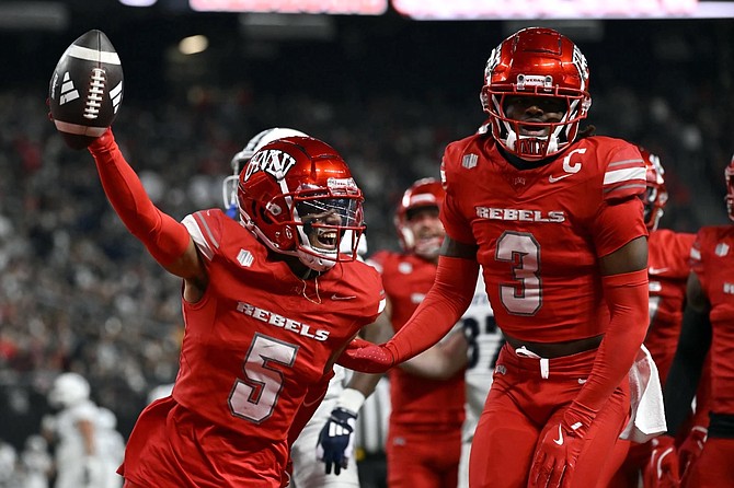 UNLV defensive backs Cameron Oliver (5) and Johnathan Baldwin celebrate Oliver’s first-half interception against Nevada on Saturday in Las Vegas.