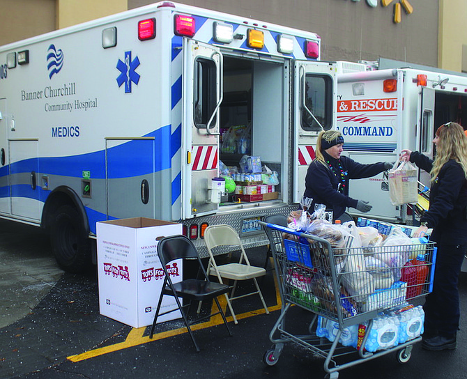 Kacy Dunckhorst, left, from Banner Churchill EMS, accepts food items during Sunday’s First Responders Food Drive.