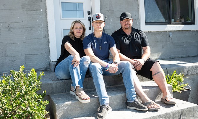 Louri Lesbo with her son Kason and husband Mike, pose for a photo outside their home in Elko.