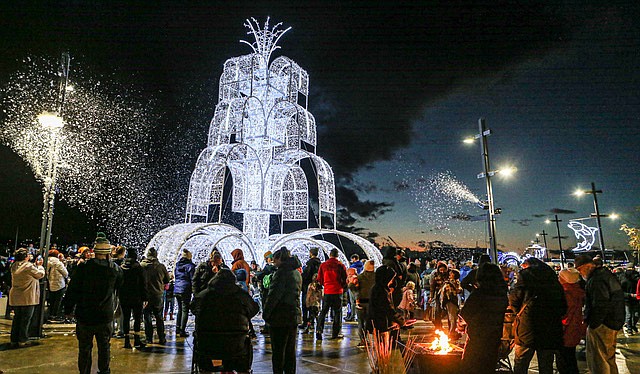 With the large Frozen Fountain Tree lighted sculpture in the background, people enjoy the 17th annual Holiday on the Bay celebration held by the Port of Everett Saturday, Dec. 7. The event included Santa and one of his elves arriving on a small boat run by the Ocean Research College Academy of Everett Community College.