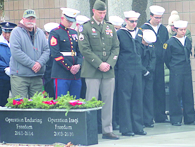 Veterans and members of the Sea Cadets from Fallon and Fernley bow their heads Saturday during the opening prayer for Wreaths Across America.