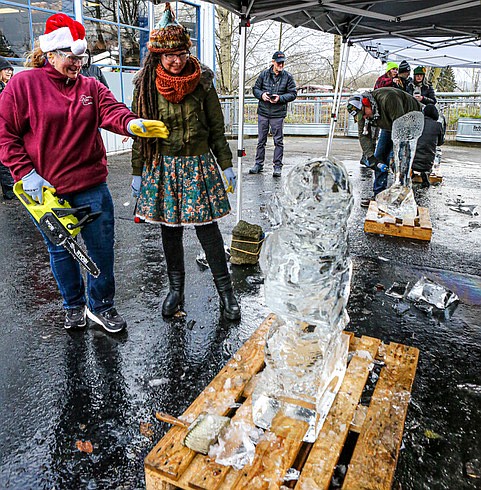 Melinda Burkhead and Kristin Harsma discuss the final details of their ice carving with a chainsaw on the afternoon of Saturday, Dec. 14 during an exhibition fundraiser at Andy’s Fish House as part of HDSA’s Snohomish Winterfest held up and down First Street in Snohomish. Other carvers included Brent Terry (working on his ice block in the center space) and Mike Capp and Justin Hillgrove (far background).