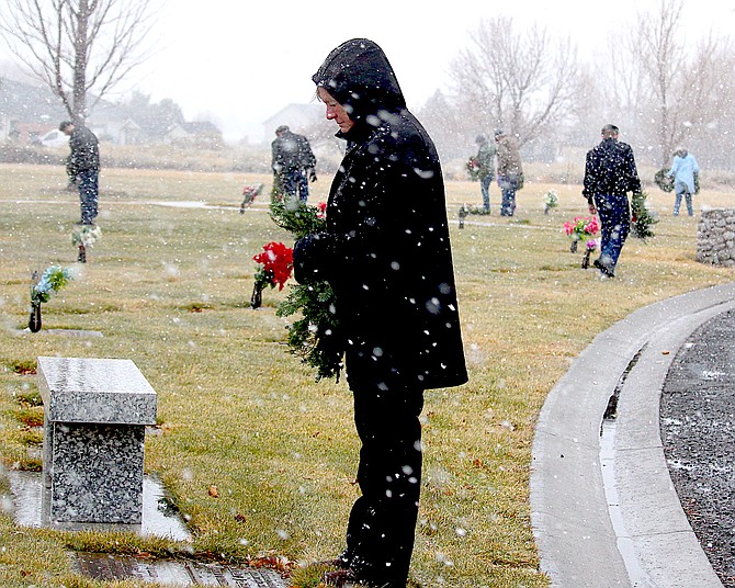 A volunteer prepares to lay a wreath on the grave of a veteran at Eastside Memorial Park in Minden.