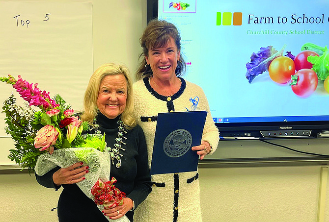 Tammy Westergard, right, senior Workforce Development Librarian-in-Residence at the Nevada Governor's Office of Economic Development, recognizes Sue Segura, the Churchill County School District’s Work Based learning coordinator, at a December meeting with a certificate of recognition and flowers for her work with students.