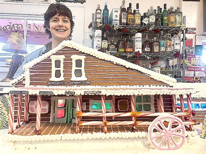 Owner Avery Hellman standing next to artist Melanie Yencken’s gingerbread model of the Markleeville General Store complete with windows and inside lights.