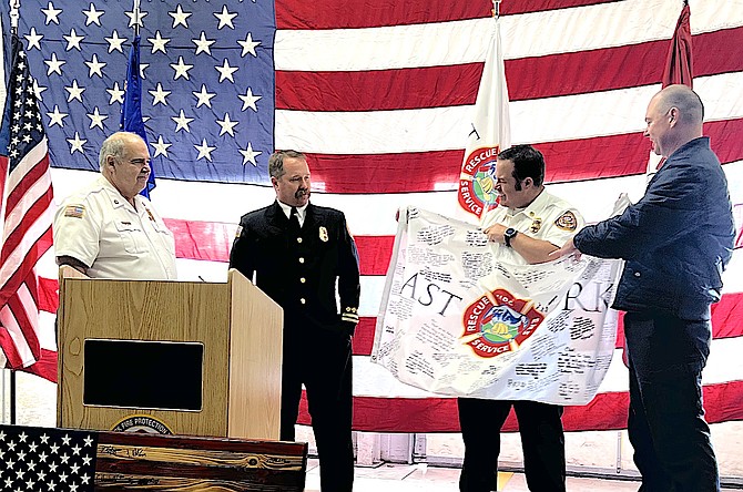 East Fork battalion chiefs present a flag signed by firefighters to Chief Tod Carlini on his retirement Friday.