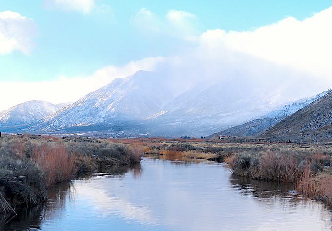 Jobs Peak is wreathed with clouds on Friday morning as reflected in Brockliss Slough below Genoa.