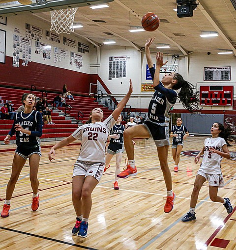 The Glacier Peak Grizzly Girls rolled over and mauled the Cascade Bruins 56 - 10 on the Bruins’ home boards, Tuesday, Feb. 11 in Everett. The hibernating Bruins scored 3 in the First Period, 7 in the Second and did not score in the Second Half.  The vast Bruin Gym was nearly empty, 
At left: Grizzly freshman guard, Faith Gamble powers a shot over Cascade’s Larissa Henry.
In the 4A Girls District Tournament:
Lake Stevens (seeded No. 2), Glacier Peak (No. 5), Arlington (No. 8) and Kamiak (No. 11) all had games after press time.
In the 4A Boys District Tournament:
Glacier Peak (seeded No. 2), Arlington (No. 5), Jackson (No. 8), and Lake Stevens (No. 11) all had games after press time.
The 4A Boys title-deciding games will be Saturday, Feb. 22 at Snohomish High.