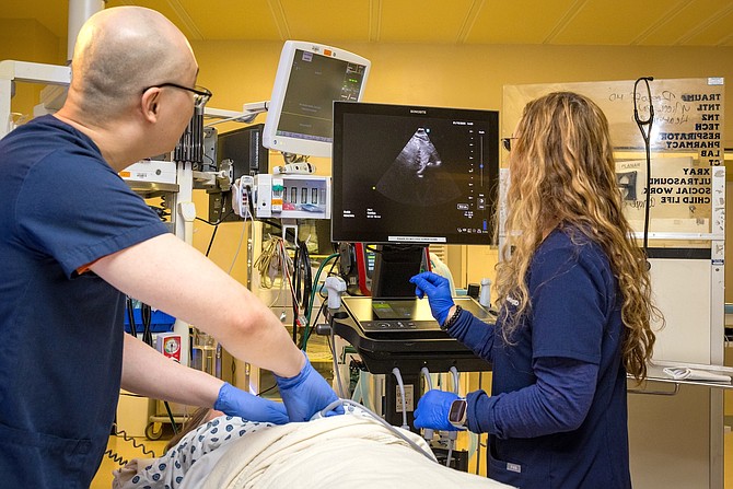 Medical resident Alan Lang (front) receives instruction from Thea Berning in the emergency room.