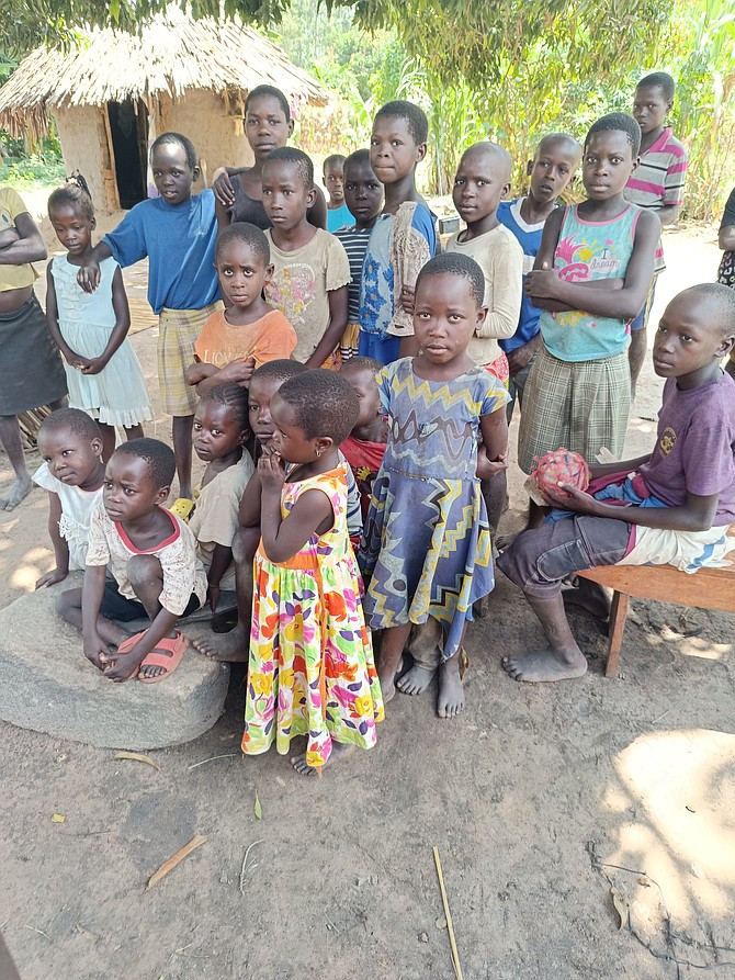 Children in Uganda who are in the village which We Heart All gave malaria nets to pose for a photo.