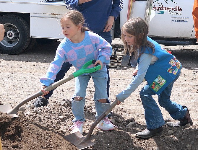 Two Girl Scouts shovel dirt in around an apple tree in Gardnerville on April  25, 2025, for Arbor Day.