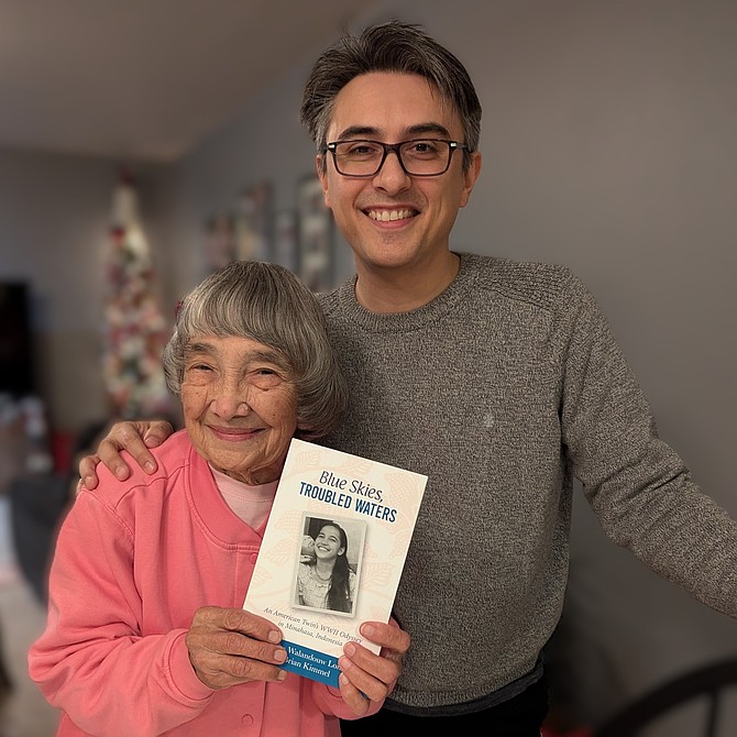 Martha Walandouw Lohn and grandson Brian Kimmel pose as Martha holds her memoir book “Blue Skies, Troubled Waters.”