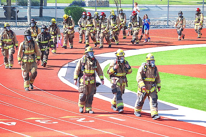 Firefighters participate in a one-bottle challenge in full gear on Sunday morning at Douglas High School.