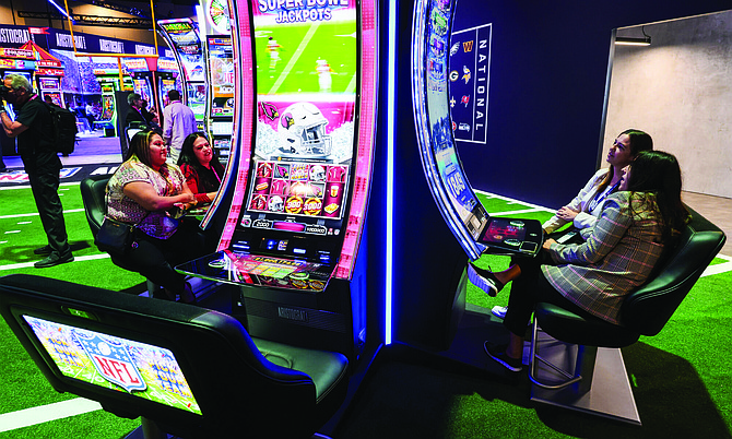 Global Gaming Expo attendees play Aristocrat Technology's NFL themed slot machines in Las Vegas on Oct. 11, 2023.