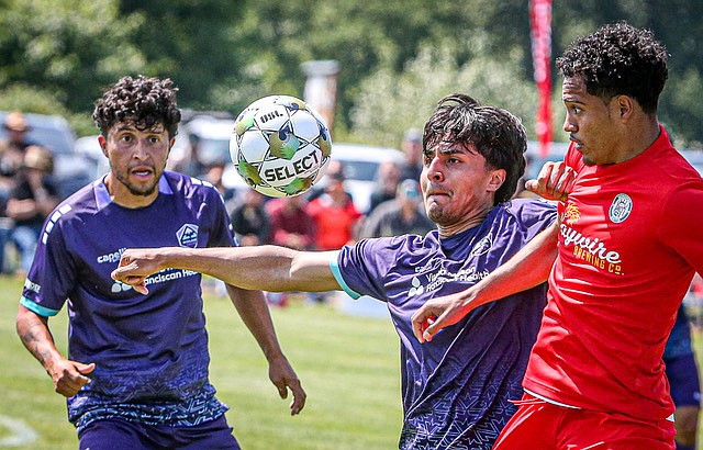 Snohomish United’s Carter Gay, in red jersey, struggles for ball control with two Midlake United players in first half action June 1 in Snohomish. Midlake, from Bellevue, won 3-1.