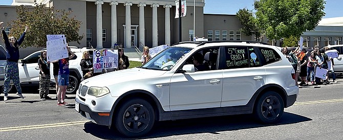 Churchill County Middle School students and staff, many wearing pink and purple in support, hold posters and cheer loudly as Kennedy Helfrich rides around the school block on May 20.
