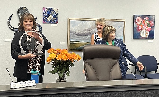 Outgoing Carson City Manager Nancy Paulson poses with flowers and a mini ‘Sense of Place’ sculpture for her official last Board of Supervisors meeting June 20, 2025. To the right, Supervisor Lisa Schuette and Mayor Lori Bagwell commemorate the occasion.