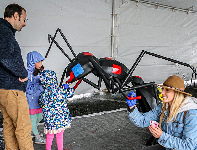 Monroe Chamber of Commerce Executive Director Janelle Drews, right, applies color to decorate an ants’ leg as part of an 
ant-themed event Saturday, June 21 at Galaxy Theaters. It included the community painting a giant ant. Frank Rimkus, CEO of Galaxy Theatres, brought many giant ants to Monroe on the first day of summer. The big ants had decorated one of his multi-plexes in Tulare, California, in greater Los Angeles, for 10 years. They languished in a warehouse until now. Rimkus said: “We worked with the Boy Scouts, Girl Scouts, Boys and Girls Clubs and others to each paint one of the ants.  The only condition we set was to ask them to paint the ants with colors and designs” which reflected each of their organizations and showed happiness.