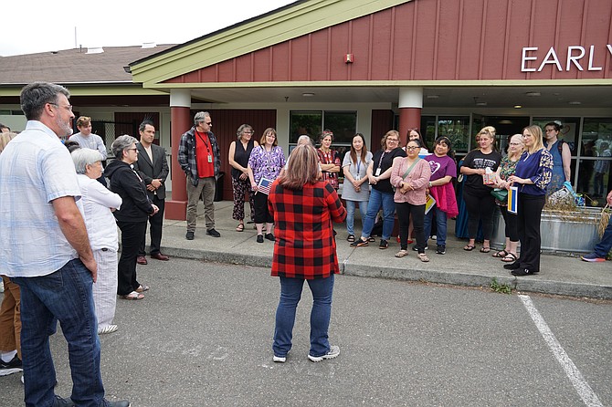 At EvCC's Early Learning Center, teacher's union leader and EvCC employee Stephanie Doyle (in checkered shirt) reads a statement to the crowd June 25 at a gathering of the Early Learning Center's final day of classes.