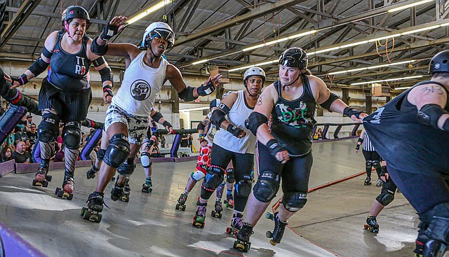 A jammer, center in white,  for the Tilted Thunder Roller Derby (TTRD) Proud Puppies team breaks through the TTRD Slappybaras team blockers in first half action of a banked track double header on Saturday, June 28 in Monroe in The Pavilion, Building 600 of the Evergreen State Fair Park. The jammer and blockers on the same team work together to let the jammer through the pack to continue to score.  The match is skated in 4, 12 minute quarters, with many team and official timeouts.  The Slappybaras held an 11-point lead at the half and ultimately won 112 - 111 at the buzzer. 
The next Tilted Thunder Roller Derby date at this track will be July 19. For more details, see www.tiltedthunder.org
