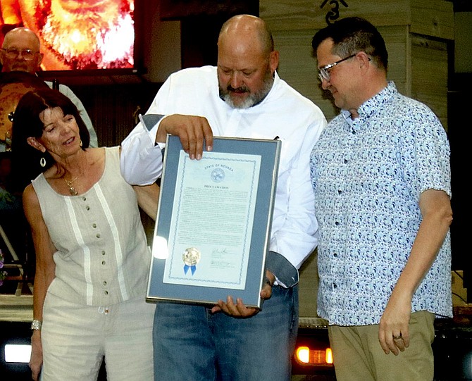 State Sen. Dr. Robin Titus, left, and Assemblyman Greg Koenig, right, present a proclamation honor retiring Churchill County Manager Jim Barbee at his June 25 retirement party.