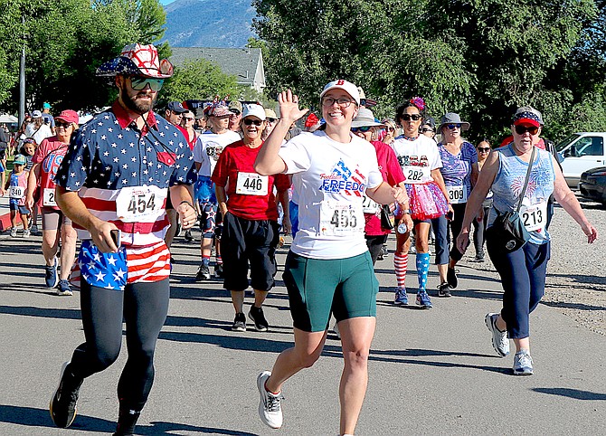 Runners wave as they make the turn from Slaughterhouse Lane to Gilman Avenue in Gardnerville for the Fourth of July 'We Run This Town' 5K.