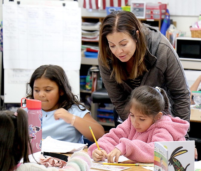 Fritsch Elementary School second-grade teacher Patricia Valdespino encourages Zara Aguirre, right, during a class assignment, with Grace Jadidi to the left in October 2025.