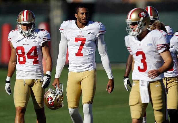 FILE - In this Aug. 2, 2013, file photo, San Francisco 49ers players, from left, Charly Martin, Colin Kaepernick, and Scott Tolzien walk on the field during NFL football training camp in Santa Clara, Calif. The man of few words, Kaepernick, has learned a thing or two from Peyton Manning. He just refuses to say what or offer any specifics. (AP Photo/Marcio Jose Sanchez, File)
