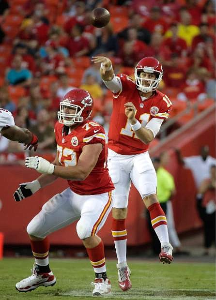Kansas City Chiefs quarterback Alex Smith (11) passes behind the blocking of offensive tackle Eric Fisher (72) during the first half of an preseason NFL football game against the San Francisco 49ers at Arrowhead Stadium in Kansas City, Mo., Friday, Aug. 16, 2013. (AP Photo/Charlie Riedel)
